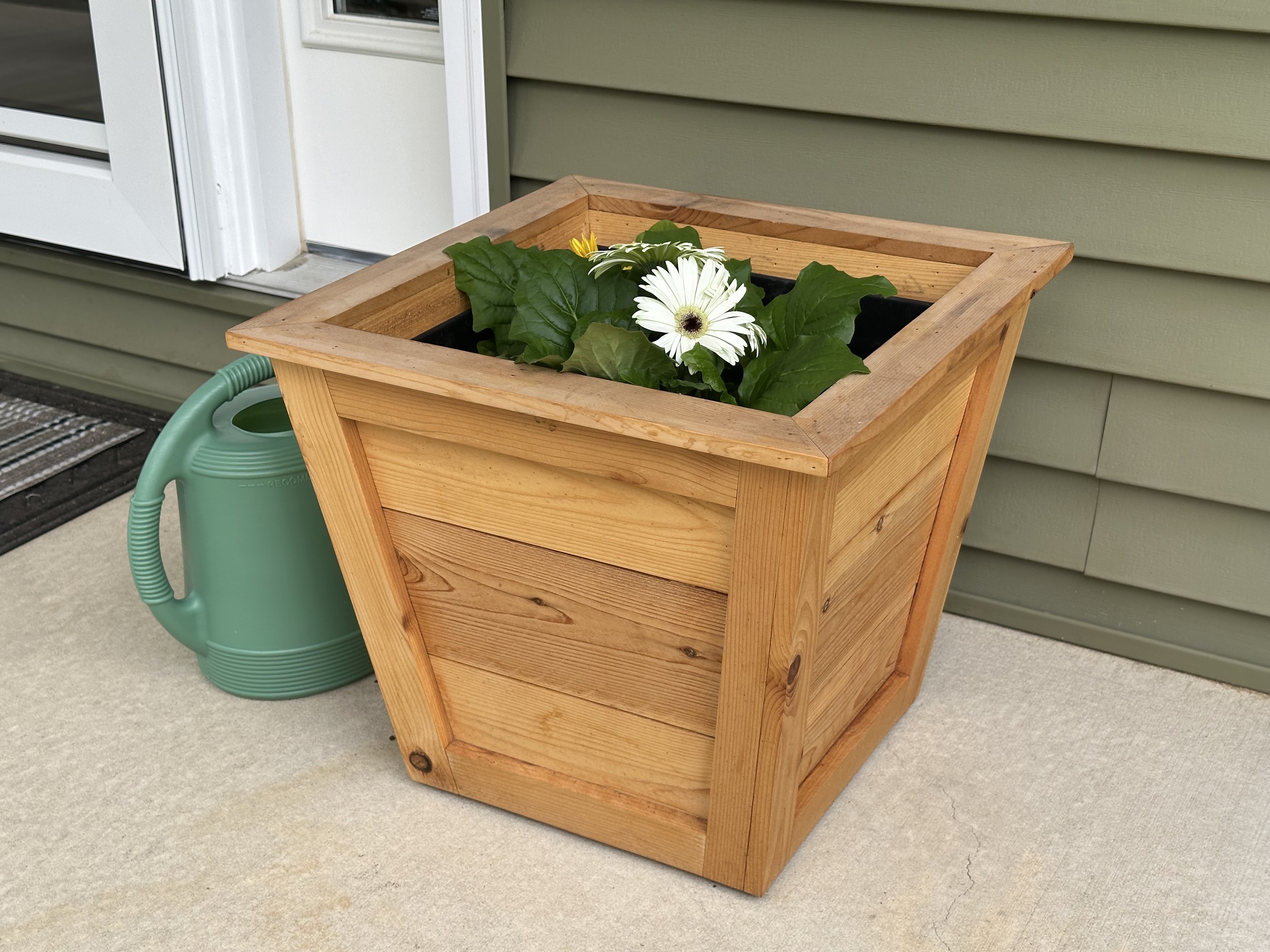 Front angle of cedar planter with flowers and watering can